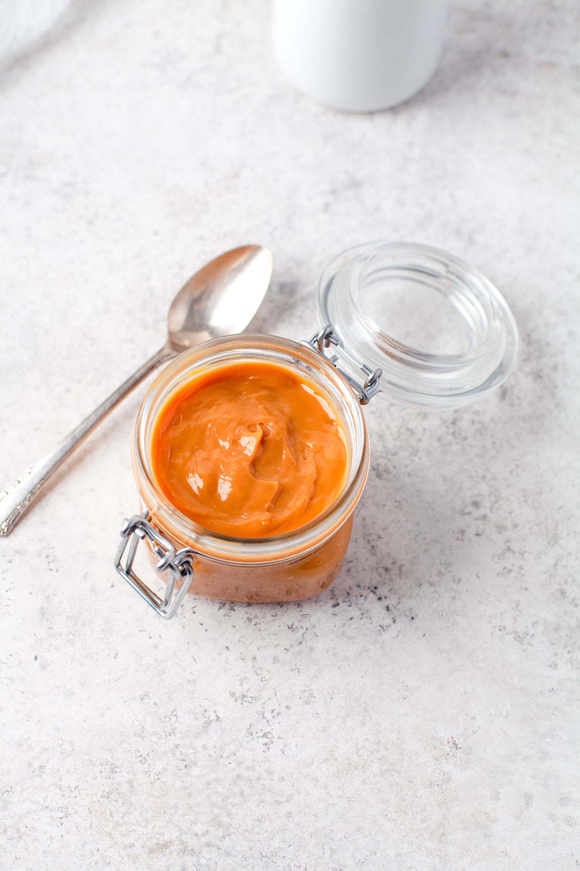 spoon next to a glass jar filled with dulce de leche
