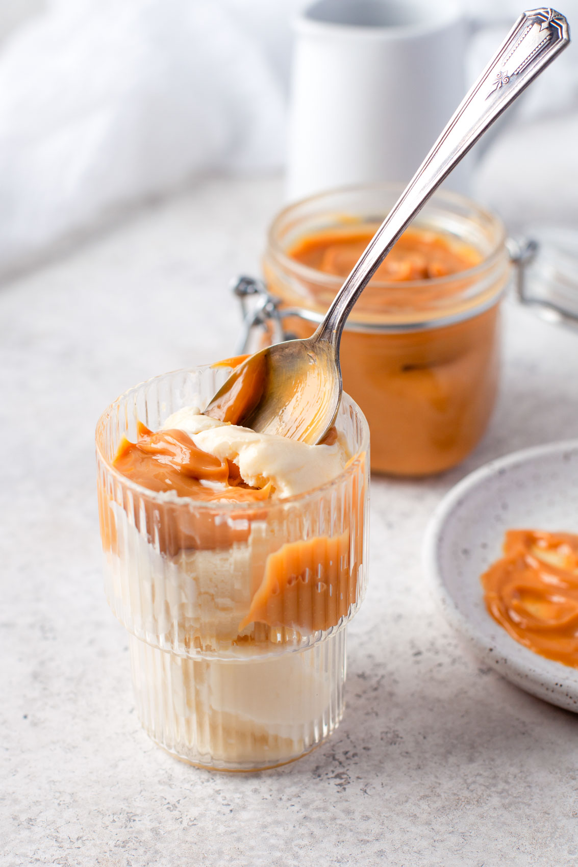 dulce de leche topping on vanilla ice cream with a spoon