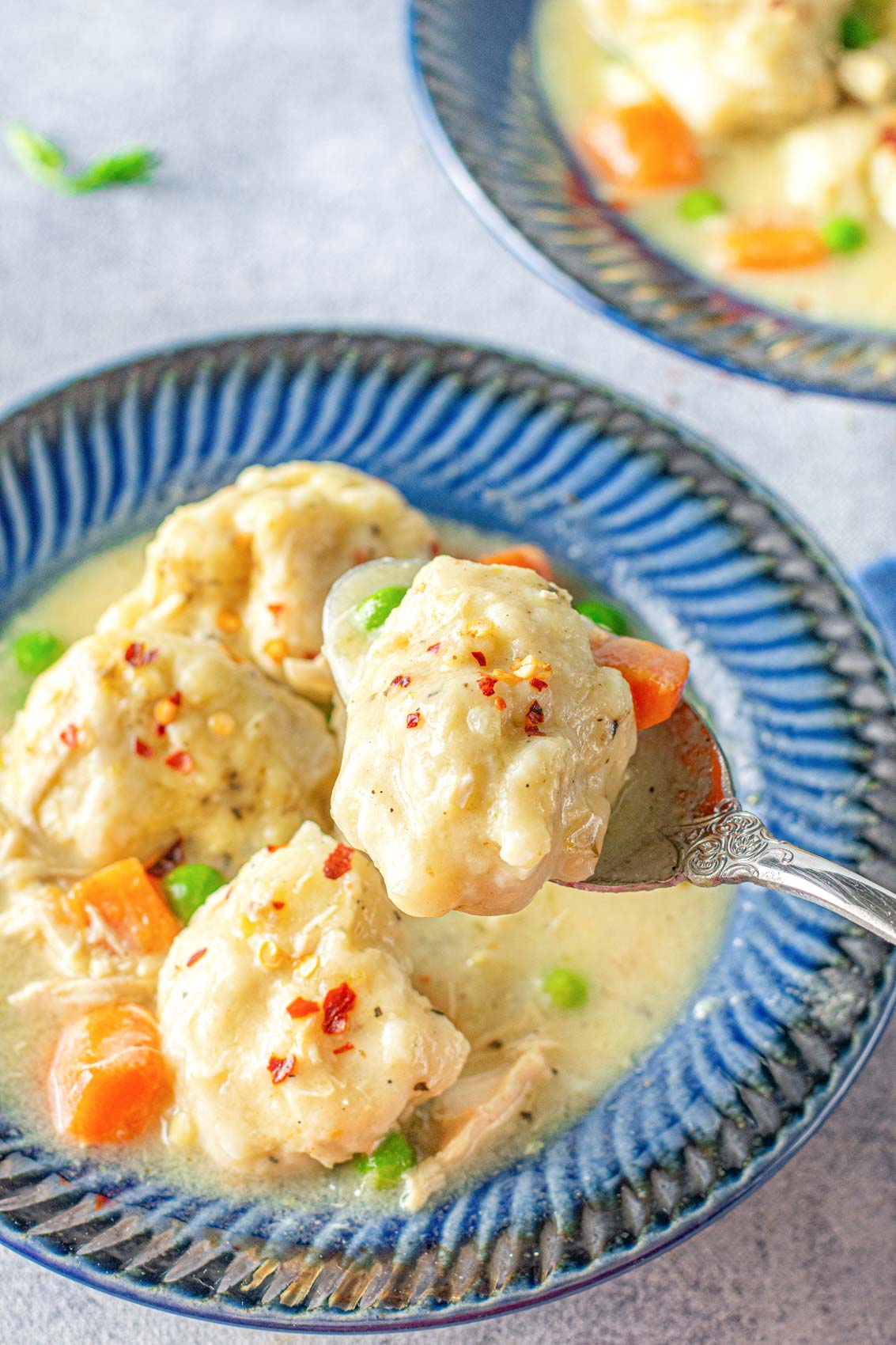 spoonful of a large dumpling and piece of carrot above a blue bowl