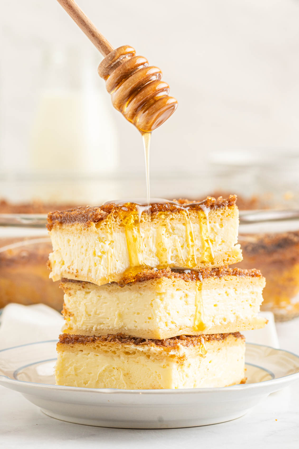 honey drizzling over three stacked sopapilas cheesecake bars