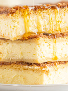 honey drizzled on top of a stack of sopapilla cheesecake bars