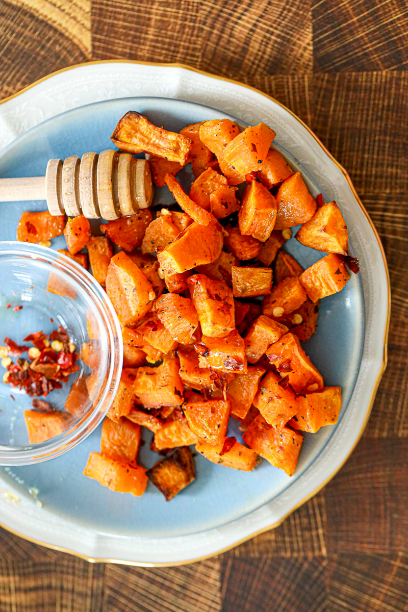 roasted sweet potato cubes next to red pepper flakes and honey