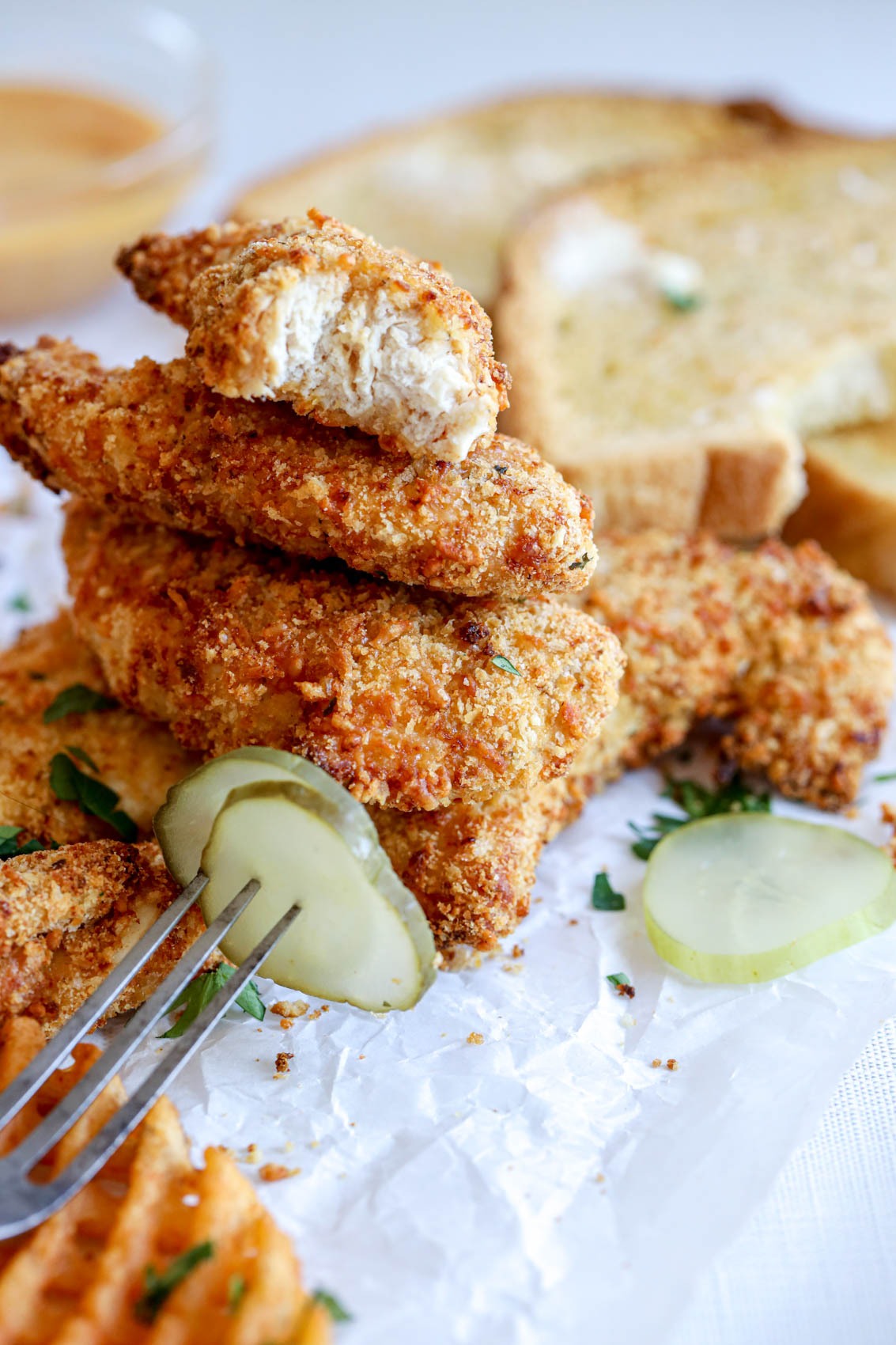 stack of three chicken tenderloins with the top one showing tender inside