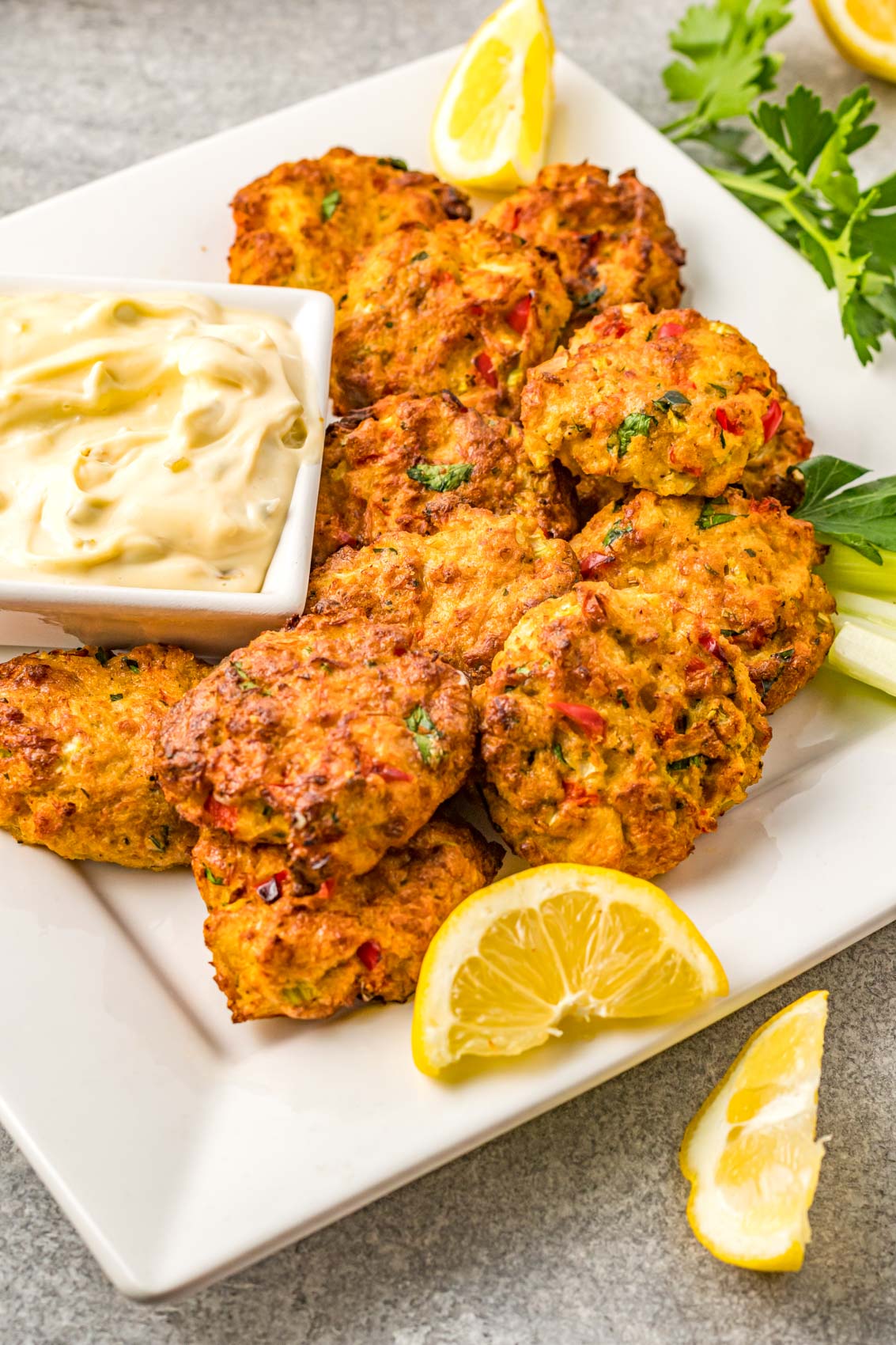 large crab cakes on a platter with a lemon wedge and tartar sauce
