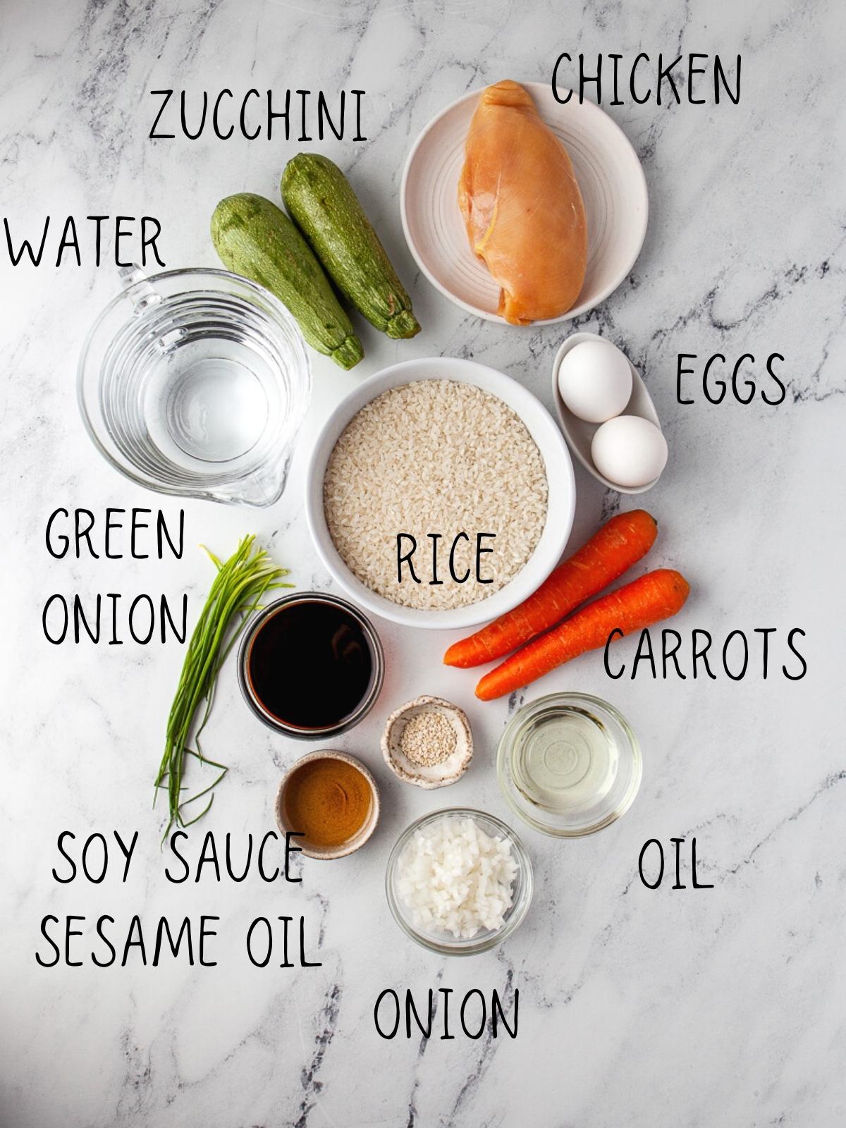 ingredients for instant pot chicken fried rice, including soy sauce, carrots, zucchini, eggs, sesame oil, and soy sauce