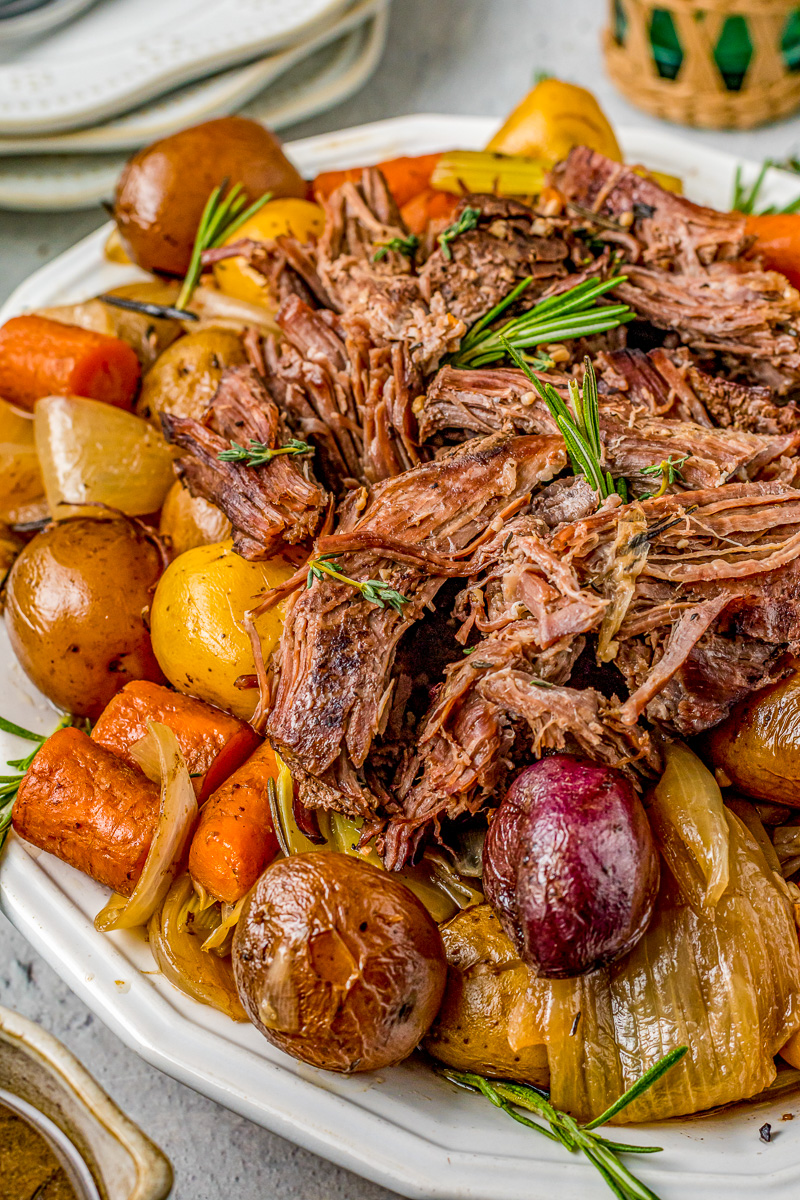 tender pot roast beef next to potatoes and carrots
