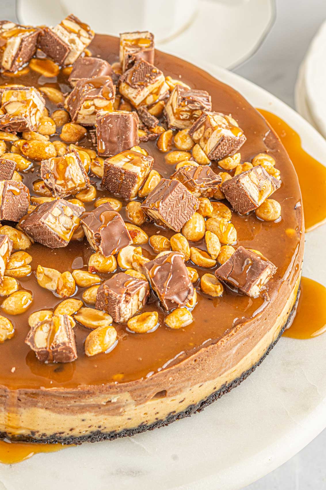top of a Snickers cheesecake, showing the chopped Snickers bars and caramel peanut topping