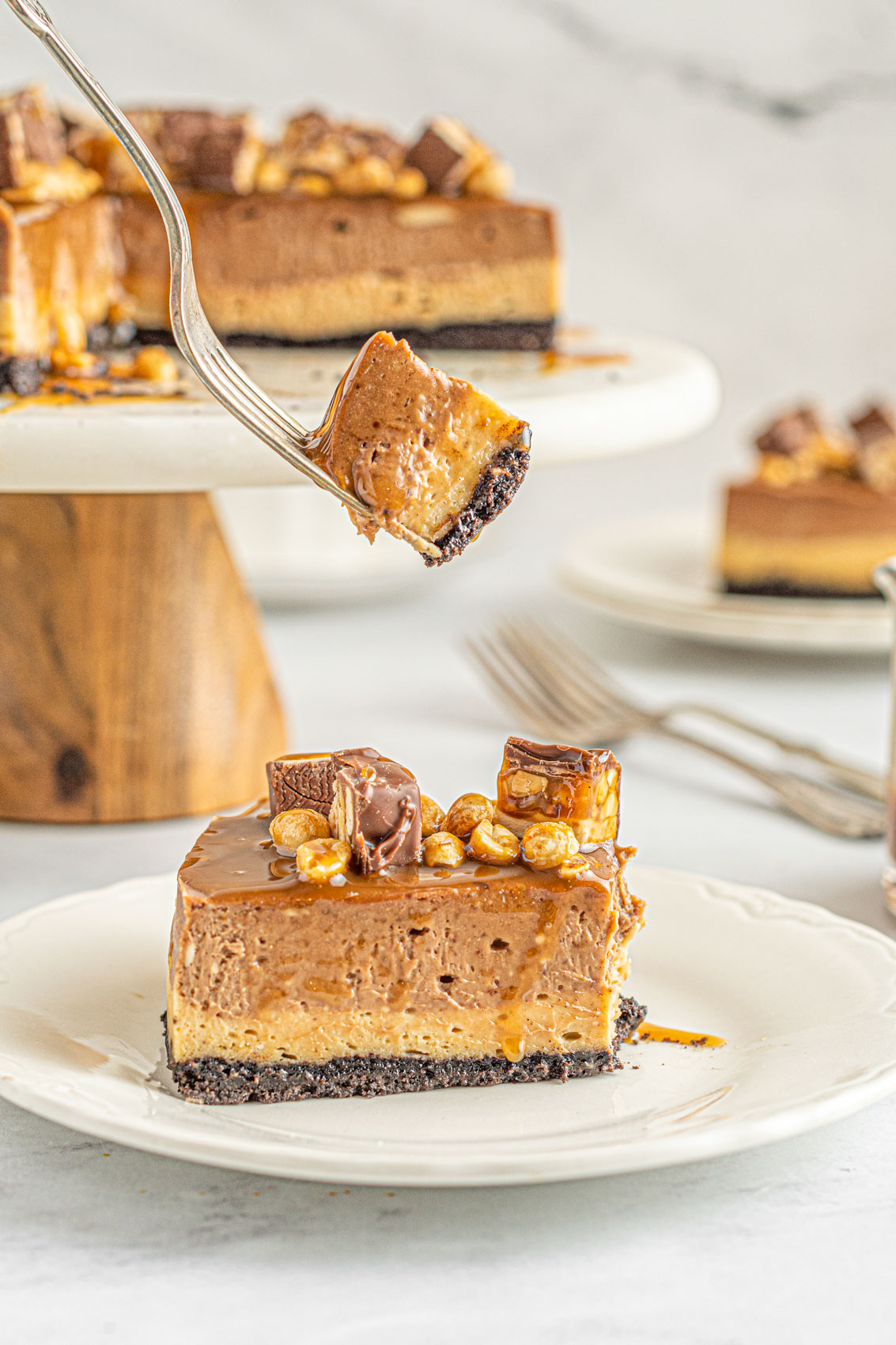 slice of snickers cheesecake covered in caramel topping