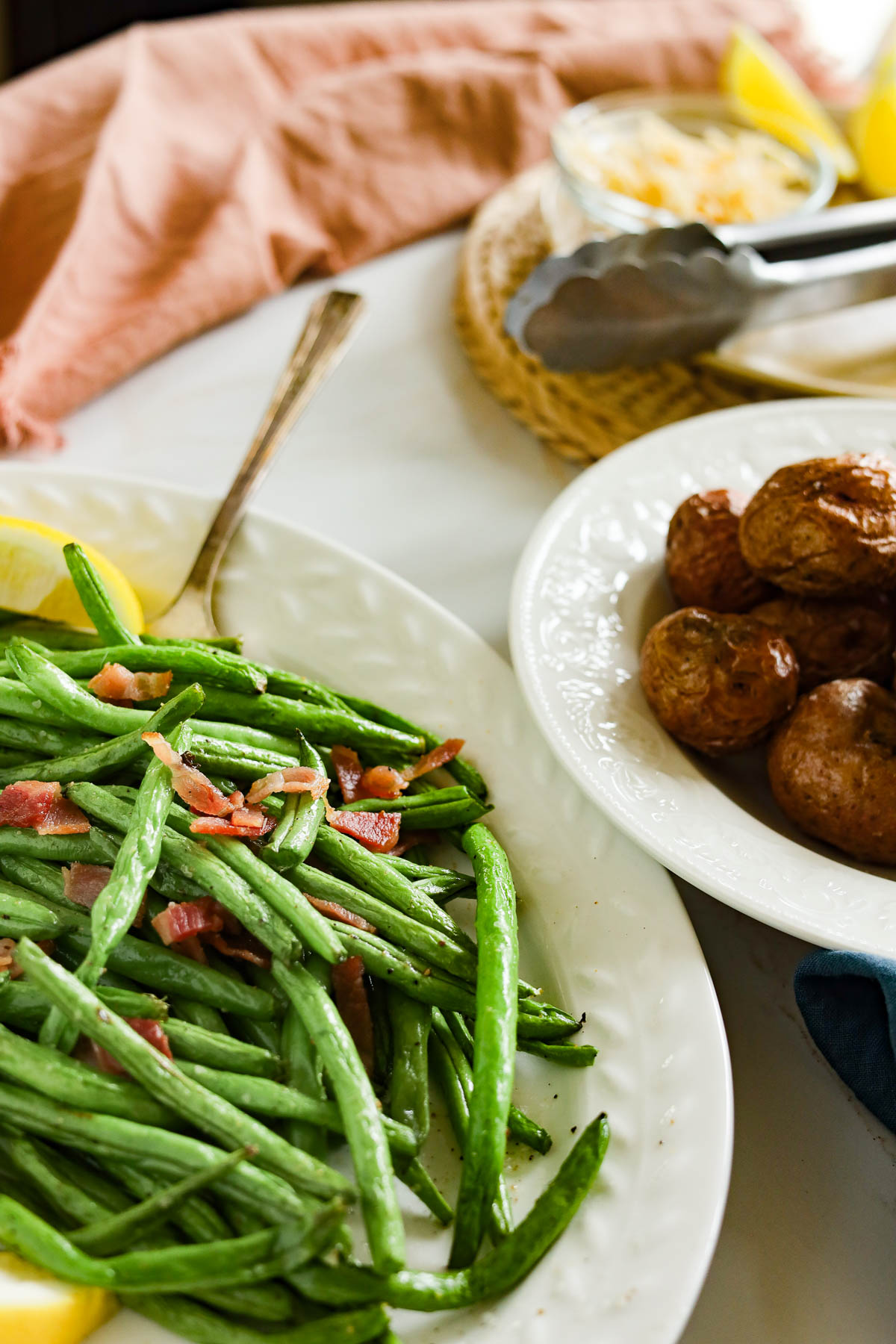 platter of green beans with bacon next to a plate of potatoes