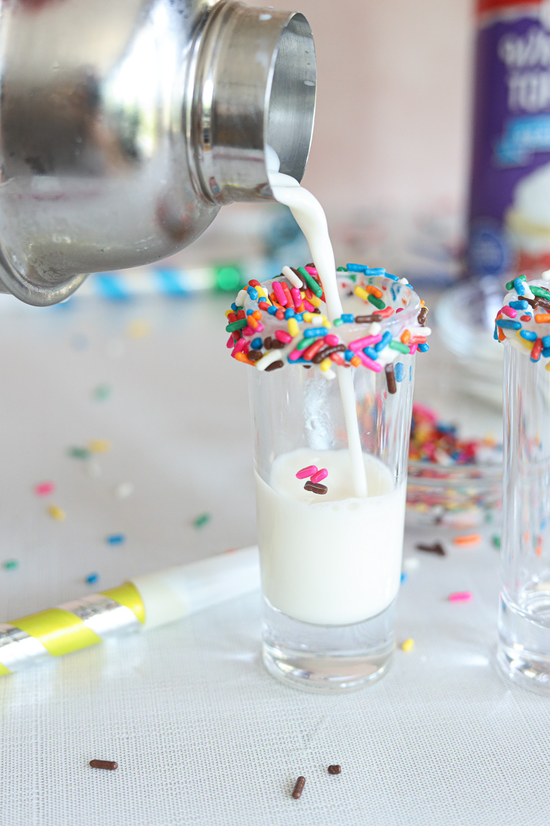 pouring a birthday cake shot into a shot glass with sprinkled rim