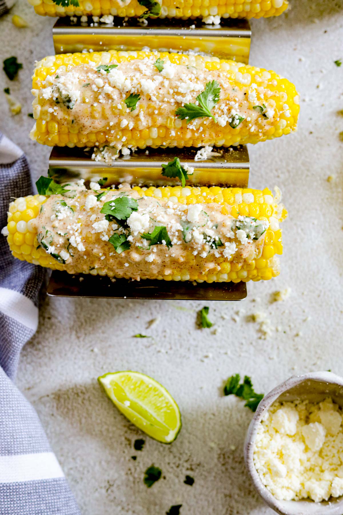 cotija cheese in a bowl next to street corn and a lime wedge