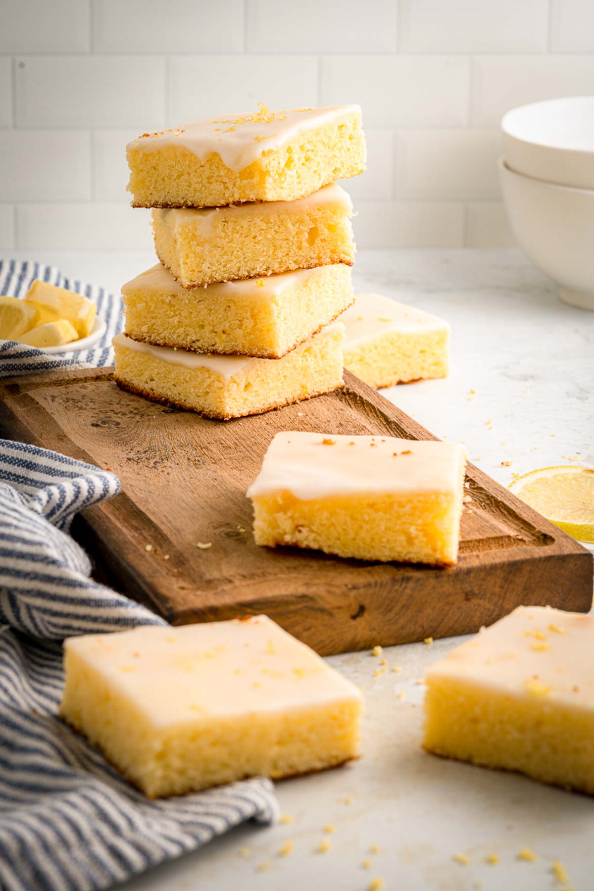 stack of glazed lemon brownies on a wooden chopping board