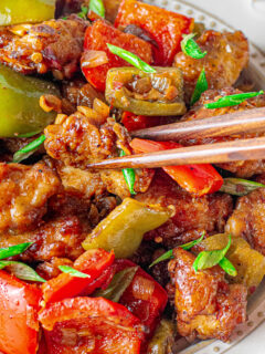 black pepper chicken with green and red bell peppers and chopsticks