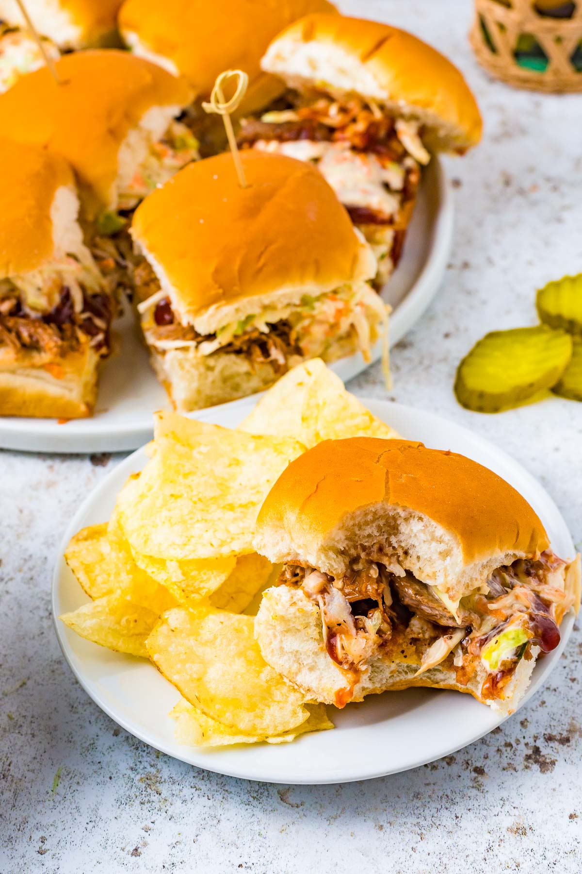 pork slider with a bite taken out on a plate with potato chips