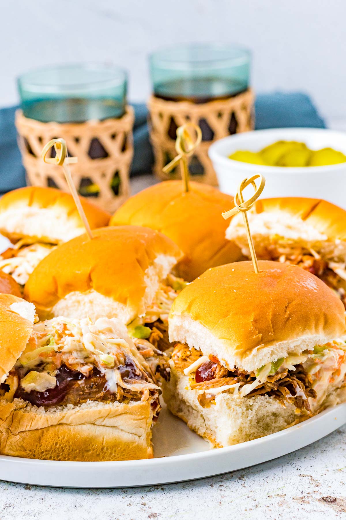 pulled pork sliders on a plate next to a side of pickles