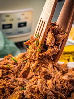slow cooker pork butt being lifted with tongs