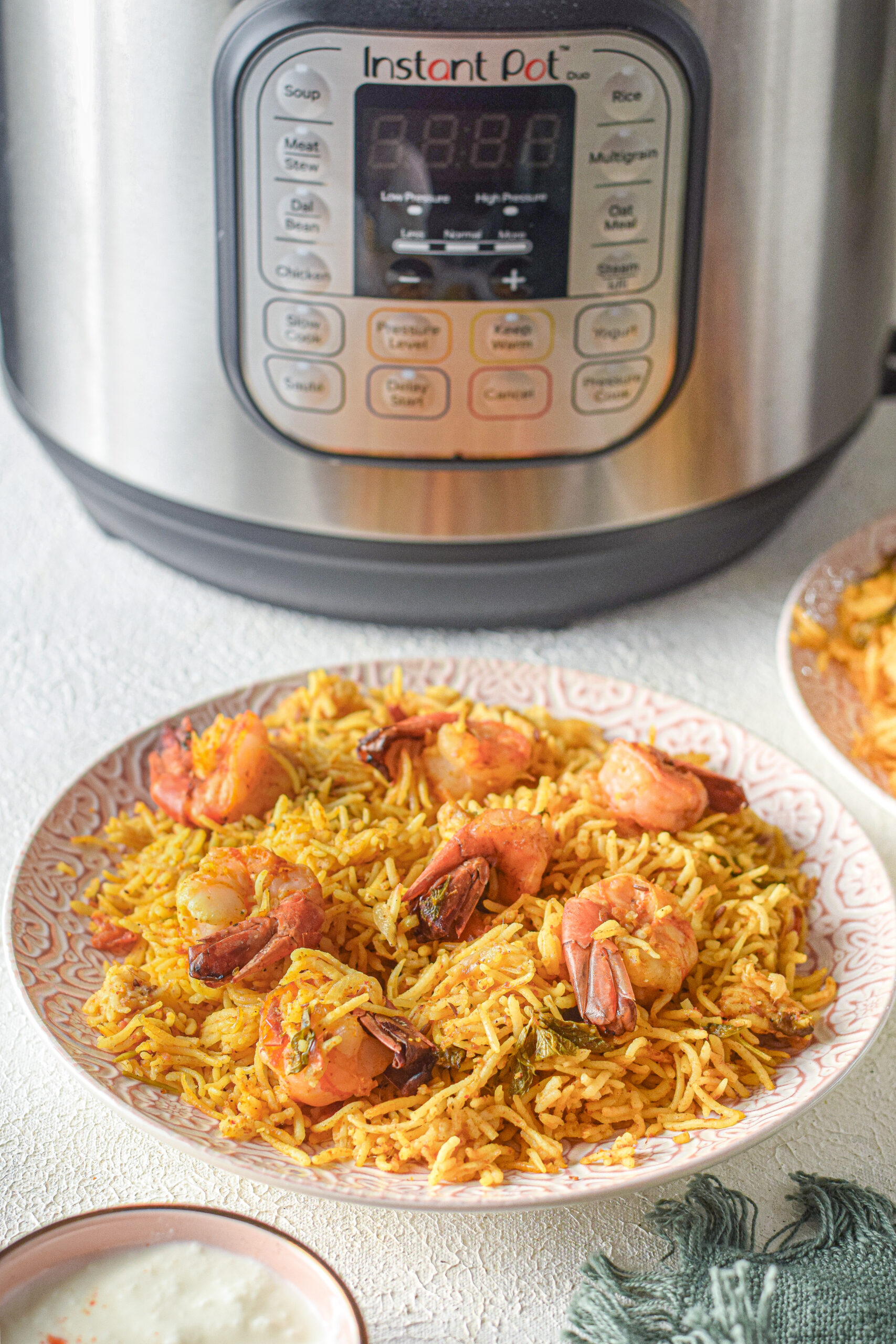 bowl of shrimp biryani sitting in front of an Instant Pot