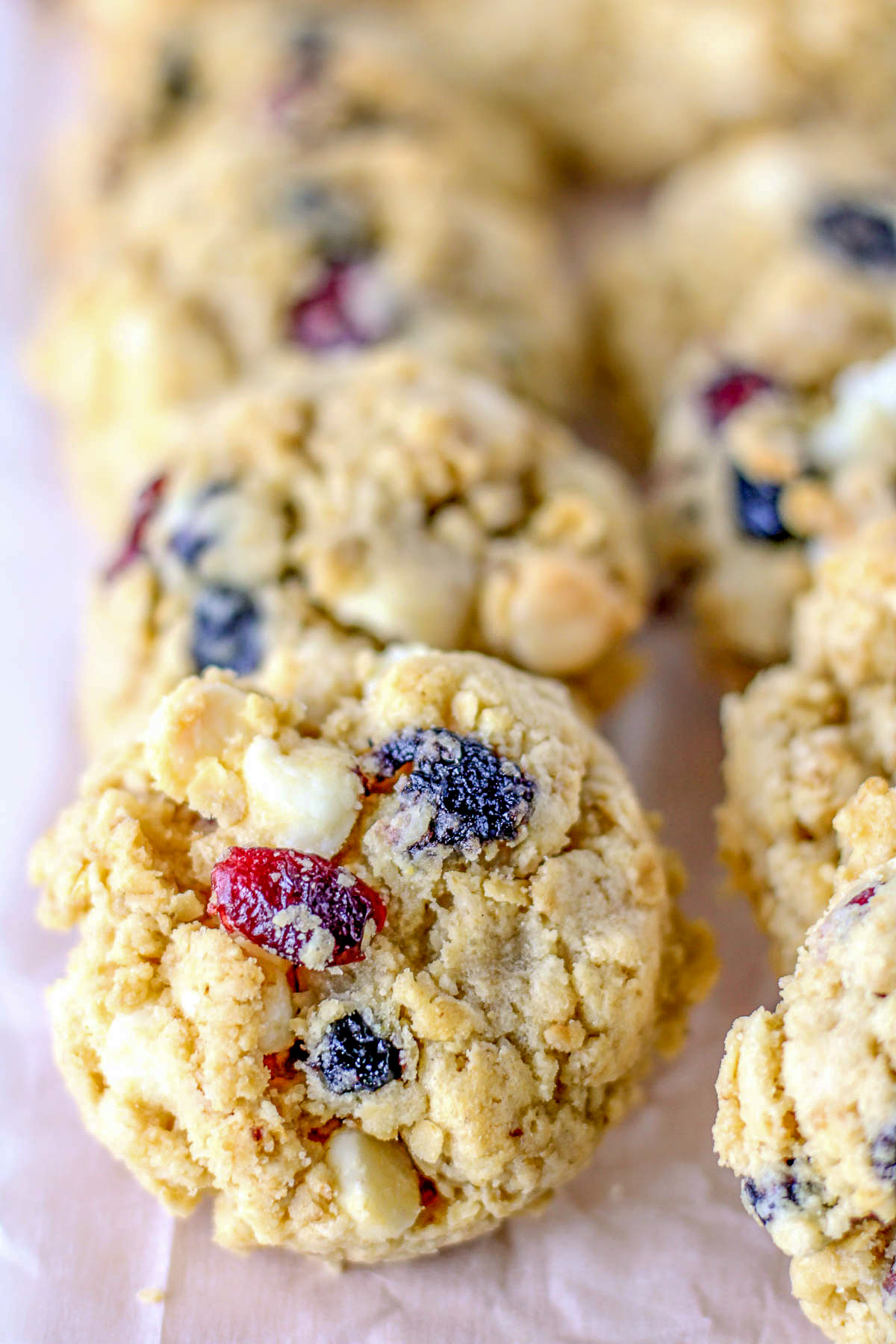 white chocolate oatmeal blueberry cookies in a row on parchment paper