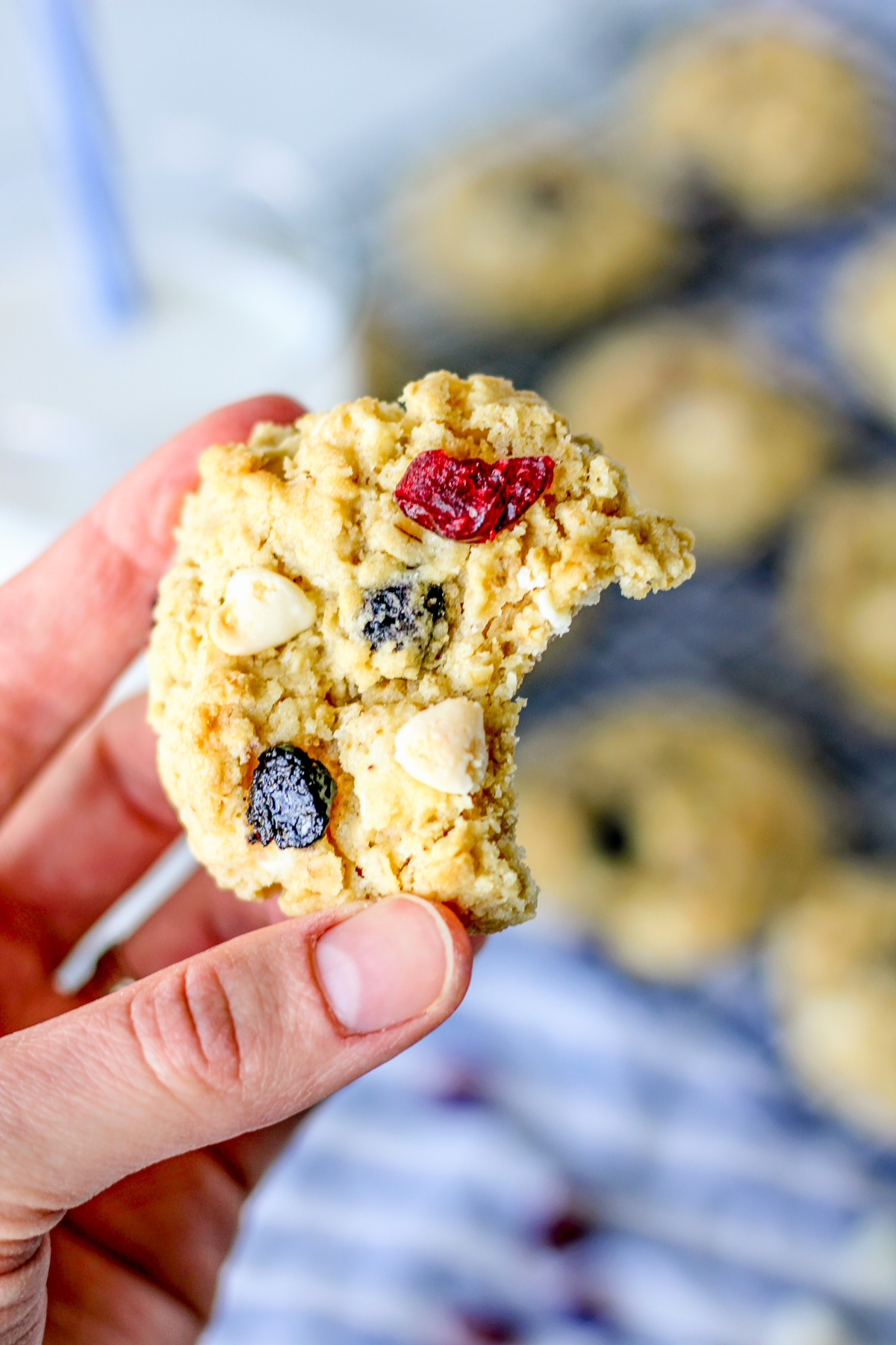hand holding an oatmeal cookie with white chocolate chips, cranberries and blueberries