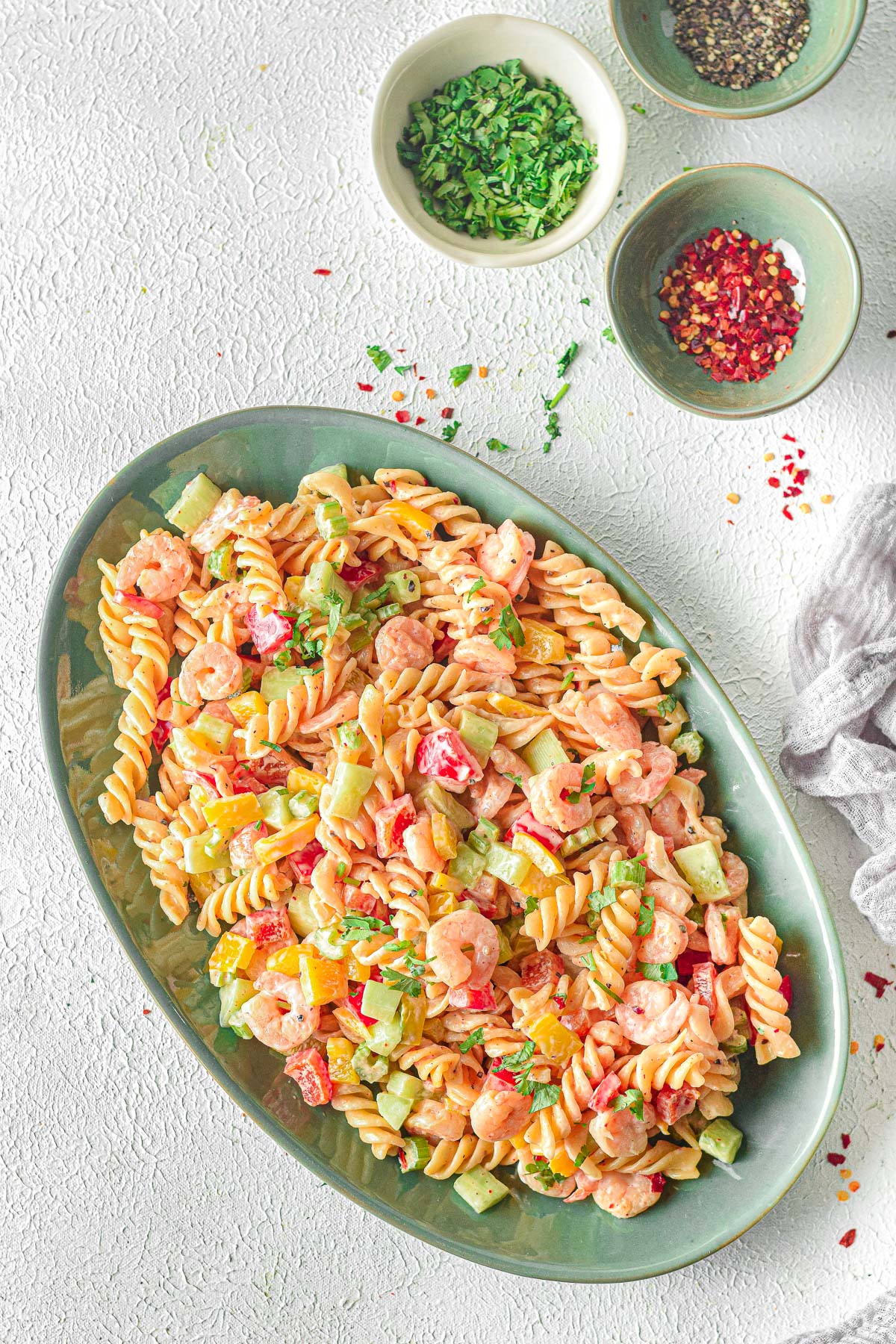 platter with shrimp pasta salad, red pepper flakes and kitchen linen