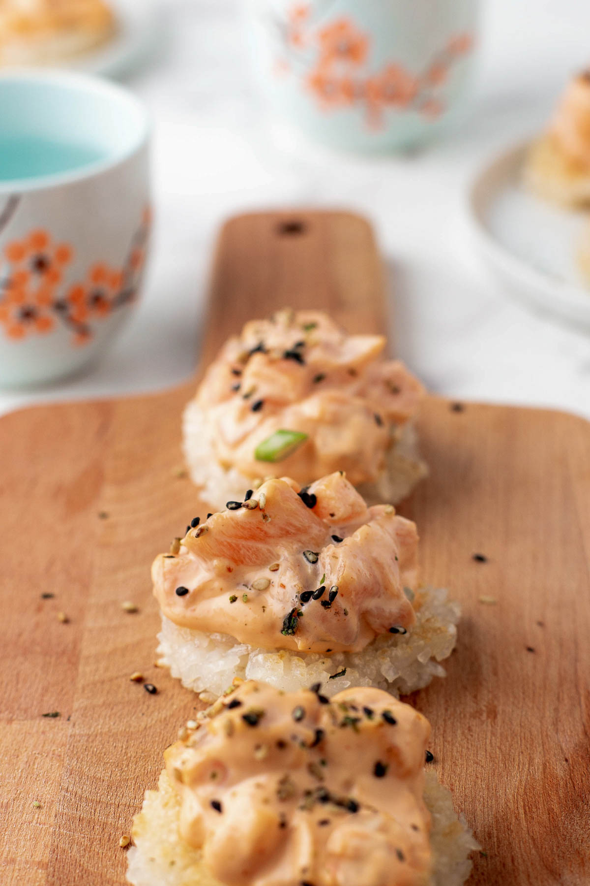 spicy salmon on fried rice cakes served on a wooden board