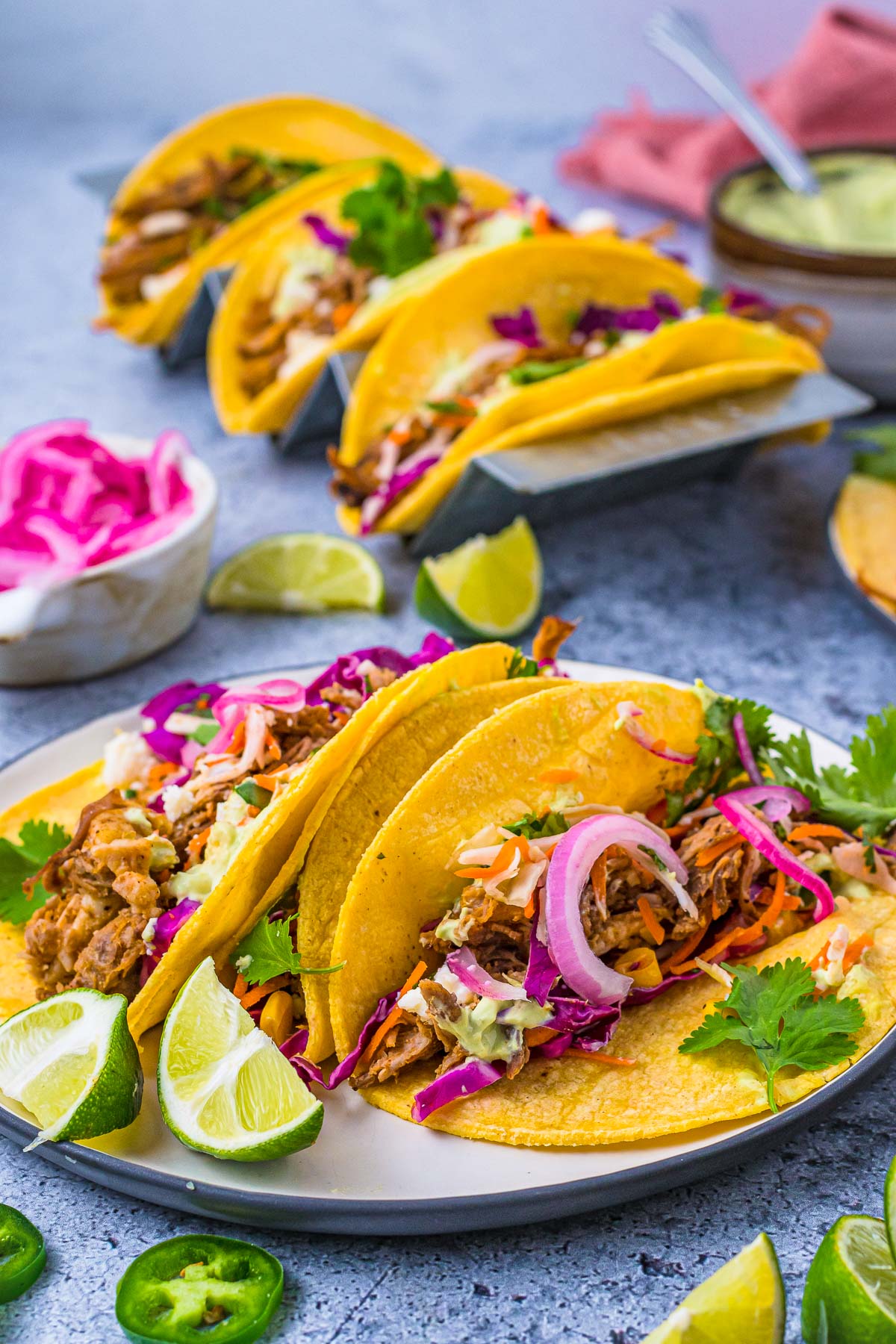 tacos in a taco stand with lime wedges and pickled red onion